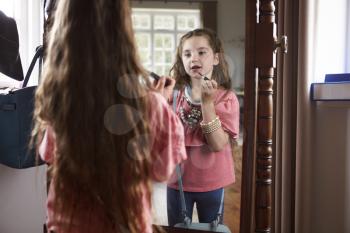 Young Girl Playing Dressing Up Game In Front Of Mirror At Home