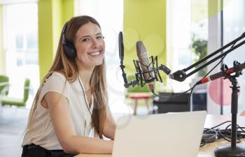 Young woman broadcasting in a studio smiling to camera