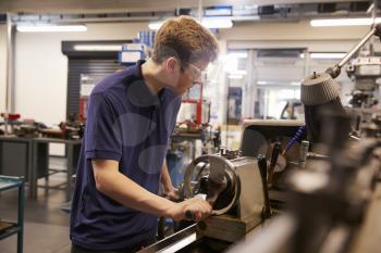 Male Teenage Apprentice In Engineering Factory Using Lathe