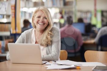 Portrait Of Mature Female Student Using Laptop In Library