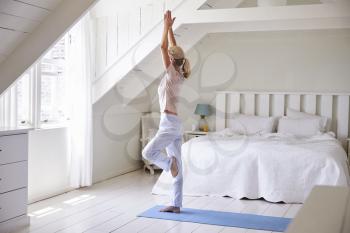 Woman At Home Starting Morning With Yoga Exercises In Bedroom