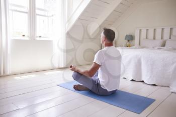 Mature Man With Digital Tablet Using Meditation App In Bedroom