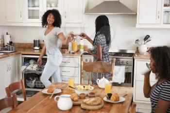 Three Teenage Girls Clearing Table After Family Breakfast