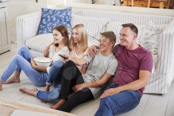 Family With Teenage Children Sitting On Sofa Watching TV Together