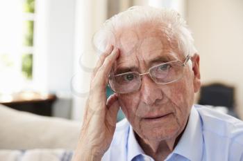 Portrait Of Senior Man Sitting On Sofa Suffering From Depression