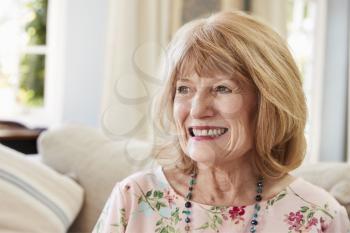 Smiling Senior Woman Sitting On Sofa At Home