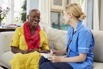 Female Community Nurse Visits Senior Woman At Home