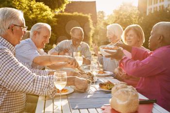 Group Of Senior Friends Enjoying Outdoor Dinner Party At Home