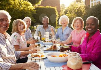Portrait Of Senior Friends Enjoying Outdoor Dinner Party At Home