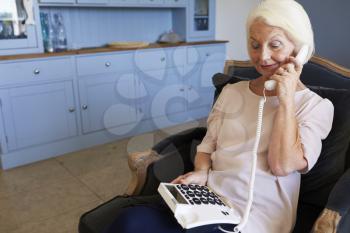 Senior Woman At Home Using Telephone With Over Sized Keys