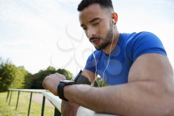 Male athlete at track checking smartwatch app, close up