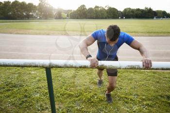 Male athlete stretching at running track, close up