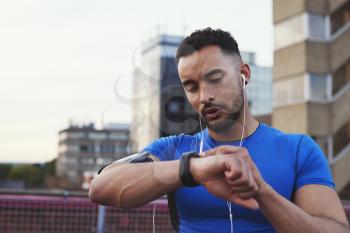 Male runner uses app on smartwatch in urban street, close up
