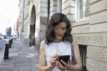 Woman in the street navigating with smartphone, waist up