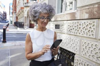Middle aged woman using smartphone in city street