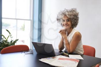Middle aged woman working in an office smiling to camera