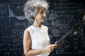 Middle aged academic woman working at blackboard