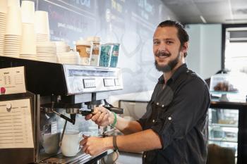 Portrait Of Male Barista Behind Counter In Coffee Shop