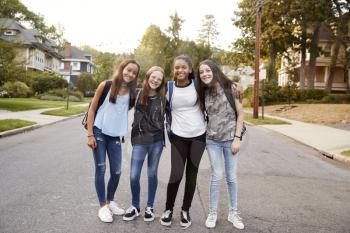 Teen girls on the way to school look to camera, full length