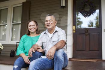 Portrait Of Smiling Senior Couple Sitting In Front Of Their Home