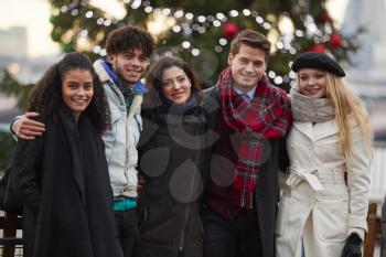 Portrait Of Young Friends On Walk Standing By Christmas Tree
