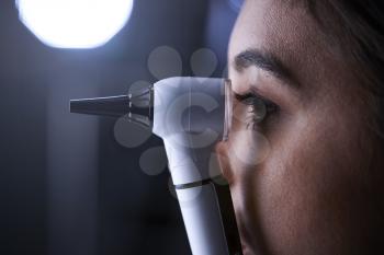 Female doctor using otoscope for examination, side view