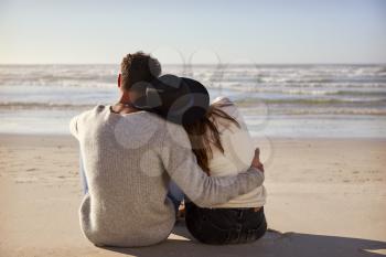Romantic Couple Sitting On Winter Beach Together