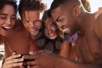 Friends On Beach Vacation Looking At Photo On Mobile Phone