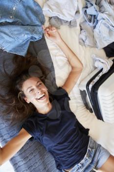 Overhead View Of Woman Lying On Bed Packing For Vacation