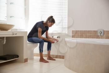 Concerned Woman In Bathroom Using Home Pregnancy Test