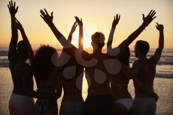 Silhouette Of Friends On Beach Vacation Watching Sunset Over Sea