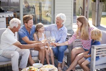 Multi Generation Family Enjoy Outdoor Drinks And Snacks At Home