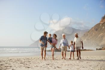 Multi Generation Family On Vacation Walking Along Beach Together