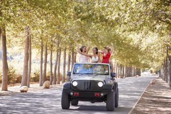 Girlfriends standing up in the back of an open top jeep