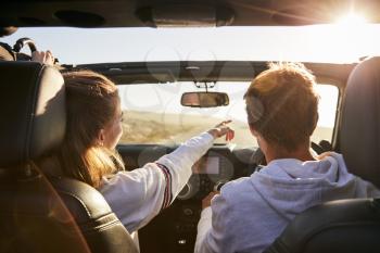 Young adult couple driving, woman pointing out directions