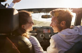 Young adult couple driving looking at each other