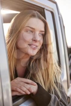 Young white woman looking away through open window of a car