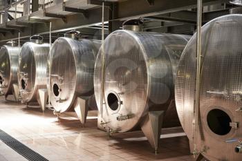 A row of metal vats in a modern winemaking facility