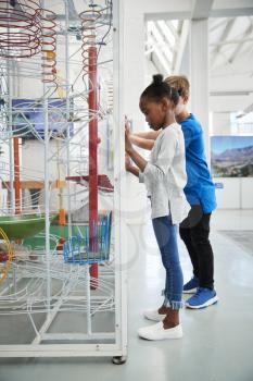 Two kids and looking at a science exhibit, vertical