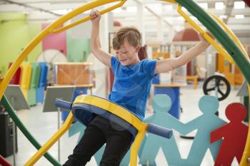 Young white boy in science centre using a human gyroscope