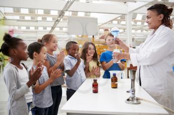 Lab technician showing excited kids a science experiment