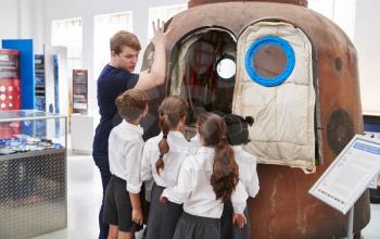 Kids and teacher look at a space capsule at a science centre