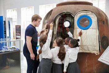 Kids and teacher look at a space capsule at a science centre