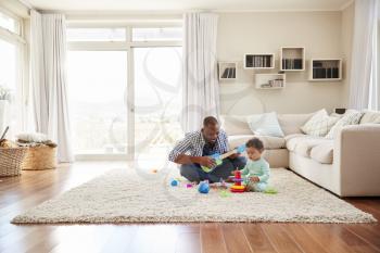 Black father and toddler son playing in the sitting room