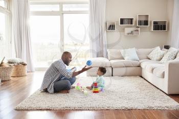 Black father and toddler son playing in sitting room