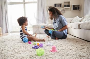 Young black mother playing with toddler daughter at home