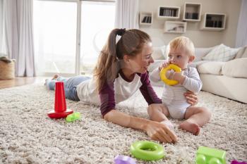 Young mother playing with toddler son on the floor at home