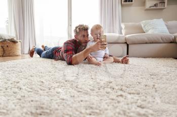 Young father taking selfie with toddler son in sitting room