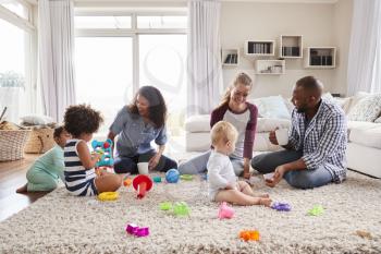 Three friends playing with toddlers on sitting room floor