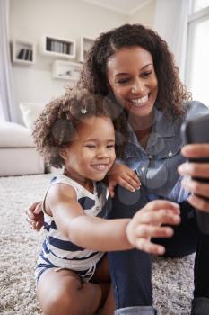 Mother and toddler daughter looking at photos on smartphone
